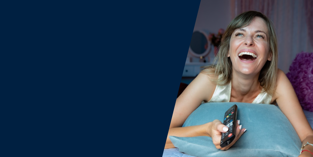 Woman laughing and watching TV internationally whose data will be collected via Nielsen's linear tv measurement.